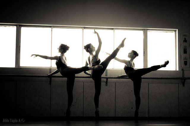 Trois danseuses classiques s'exercent à la barre.
