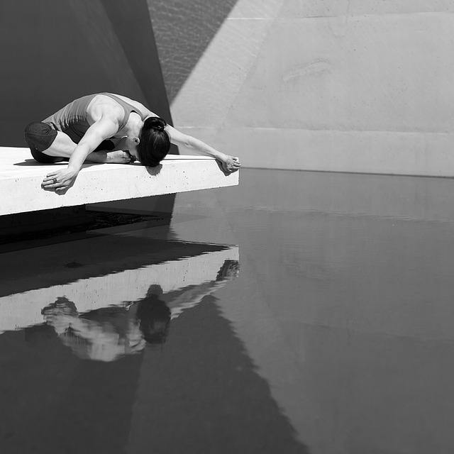 Une femme pratiquant le yoga devant une piscine.