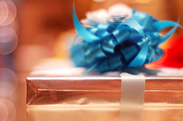 Photographie d'un paquet cadeau dans du papier doré avec un ruban bleu.